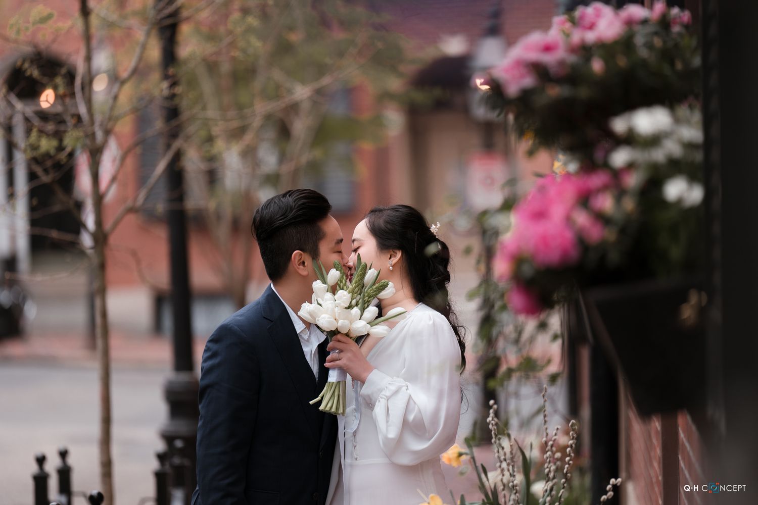 Romantic spring wedding portraits with pink cherry blossoms and brick architecture.