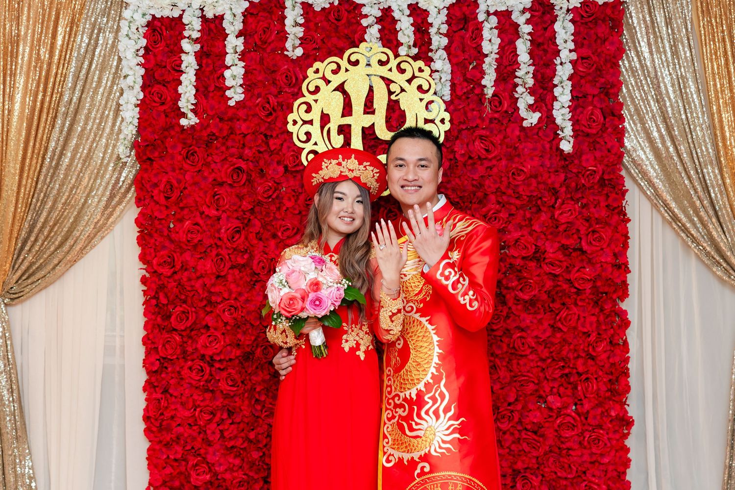 Wedding celebration with dramatic red rose wall backdrop and gold accents.