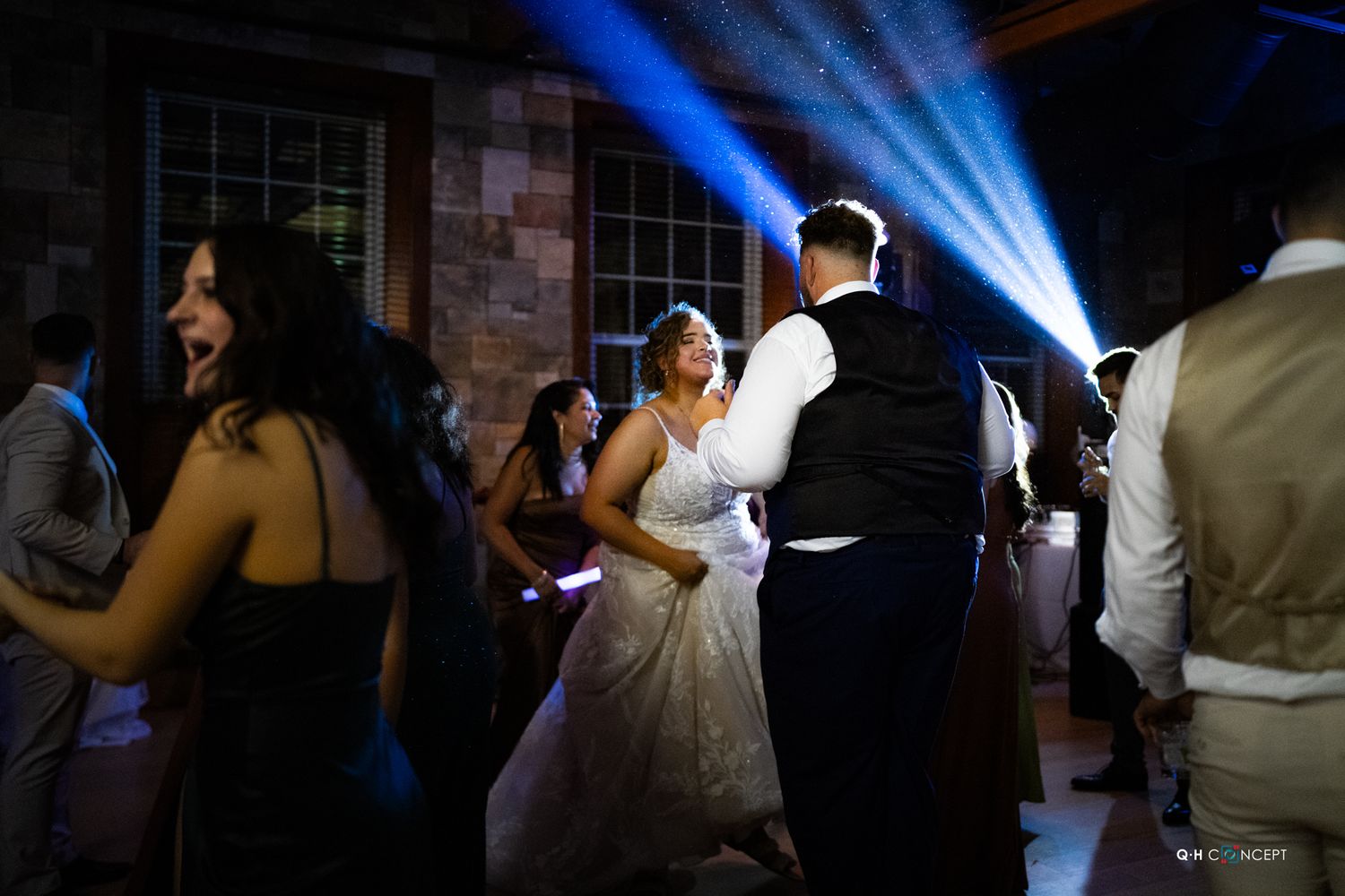 Wedding reception dance floor with dramatic blue lighting and dancing guests.