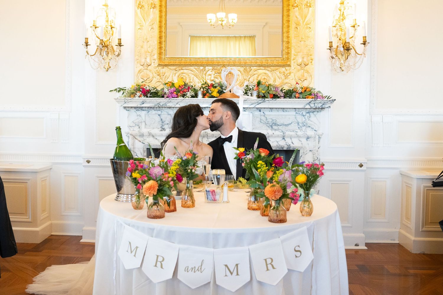 Wedding reception table settings with floral centerpieces and elegant decor in a bright white ballroom.