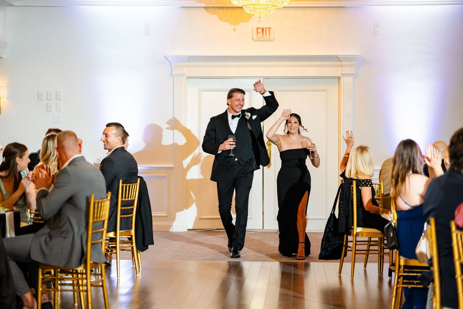 Wedding reception venue with elegant white decor and gold chiavari chairs set up for celebration.