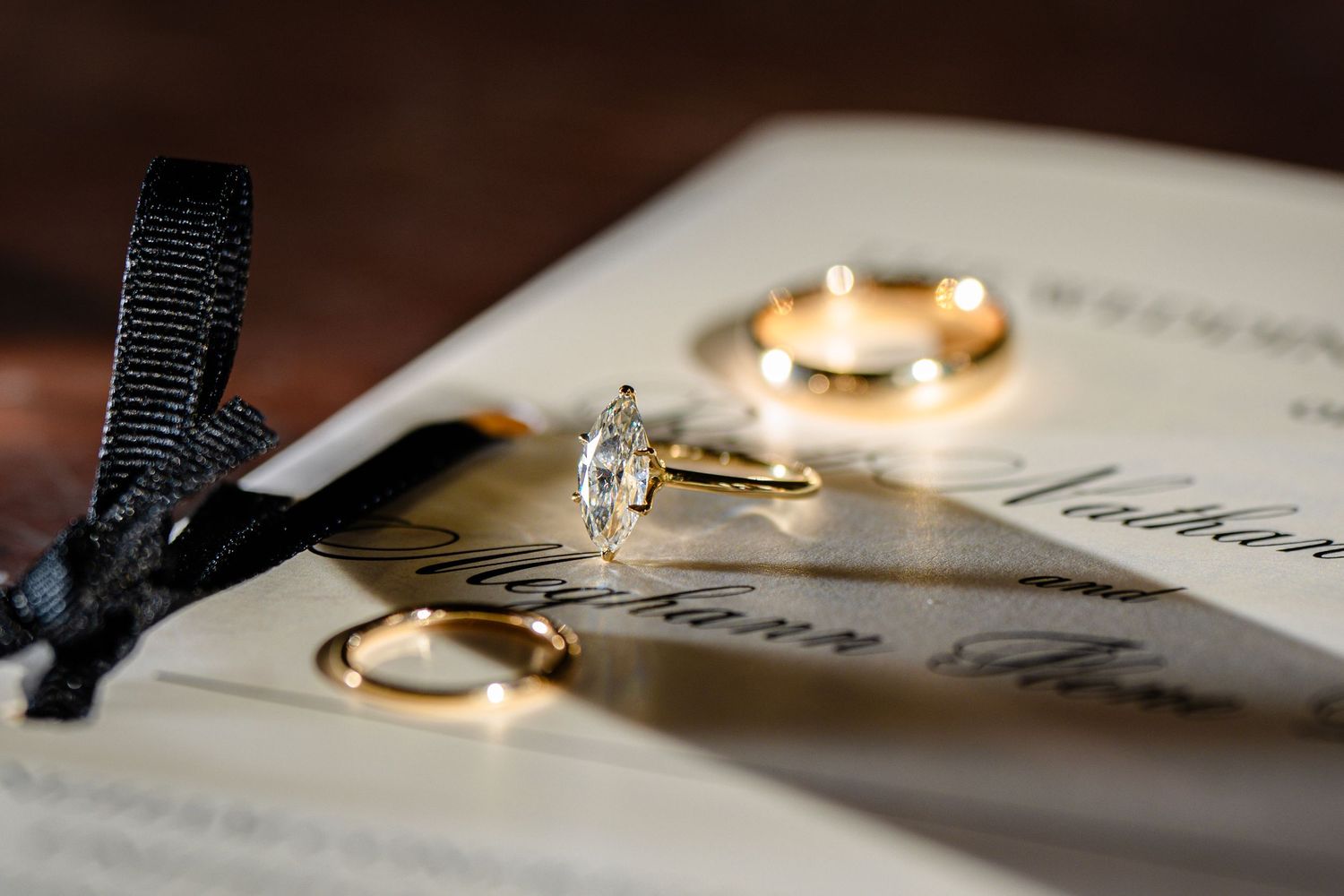 A collection of lit candles and wedding rings arranged artistically on paper with elegant calligraphy.