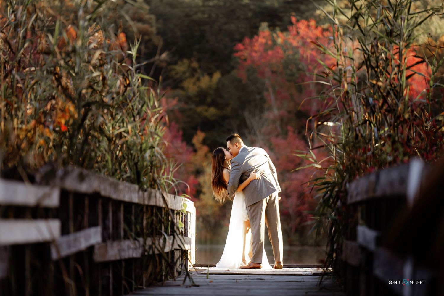 A couple poses against autumn foliage creating a romantic silhouette.