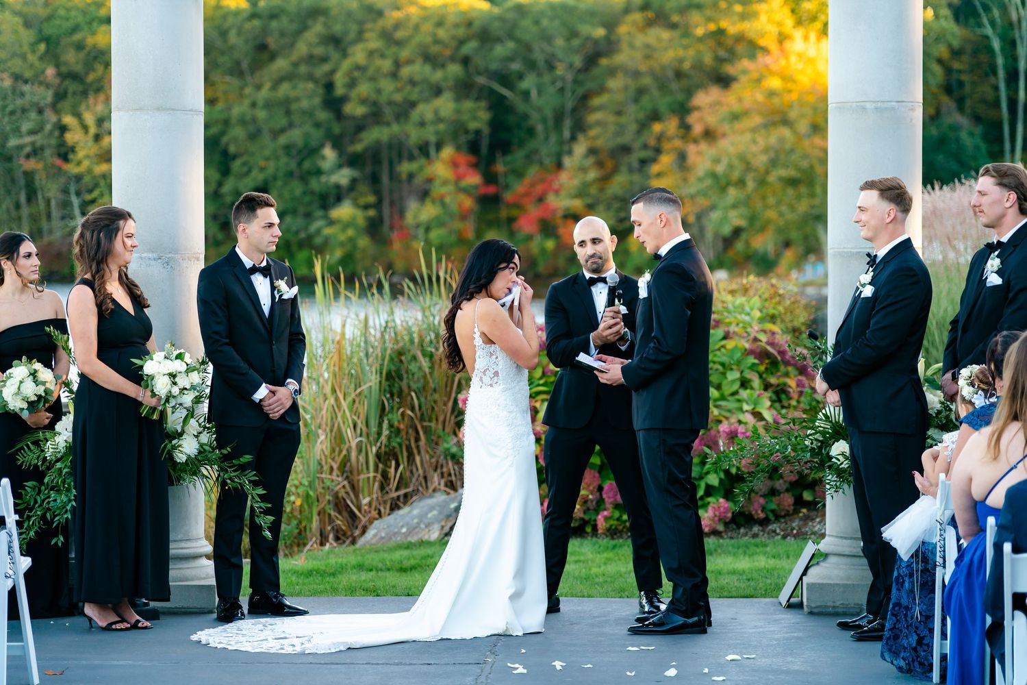 Wedding party gathered on an elegant white columned porch during an outdoor autumn ceremony.