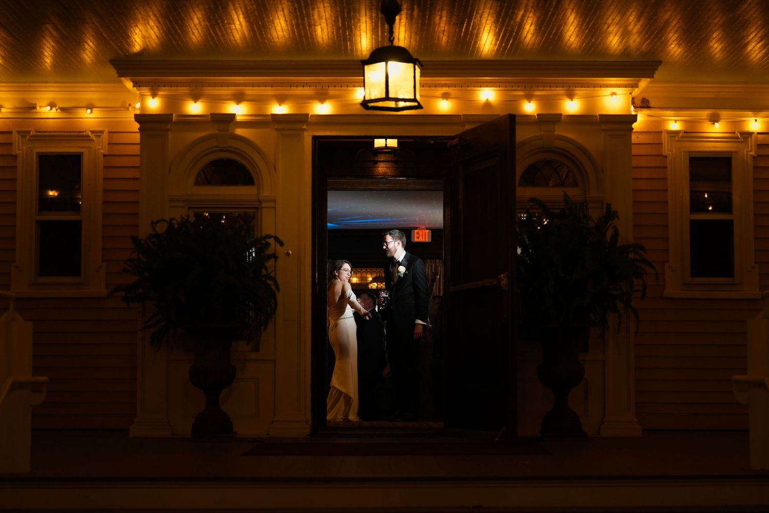 Wedding venue exterior illuminated with warm string lights at night.