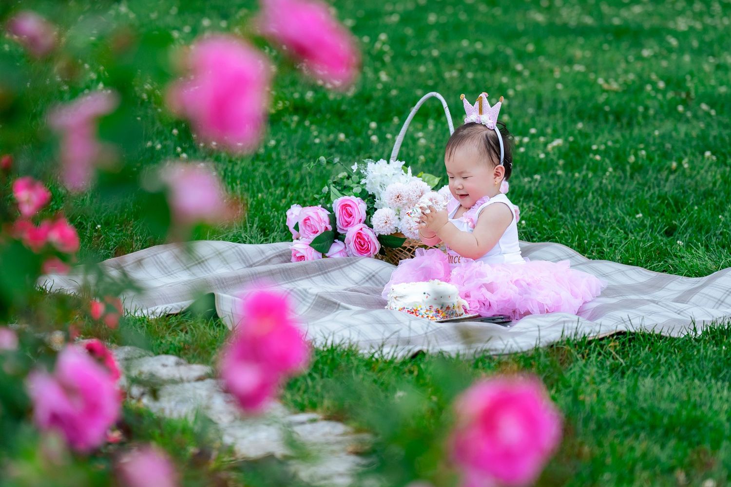 Spring family photoshoot on lawn with pink flowers in foreground.
