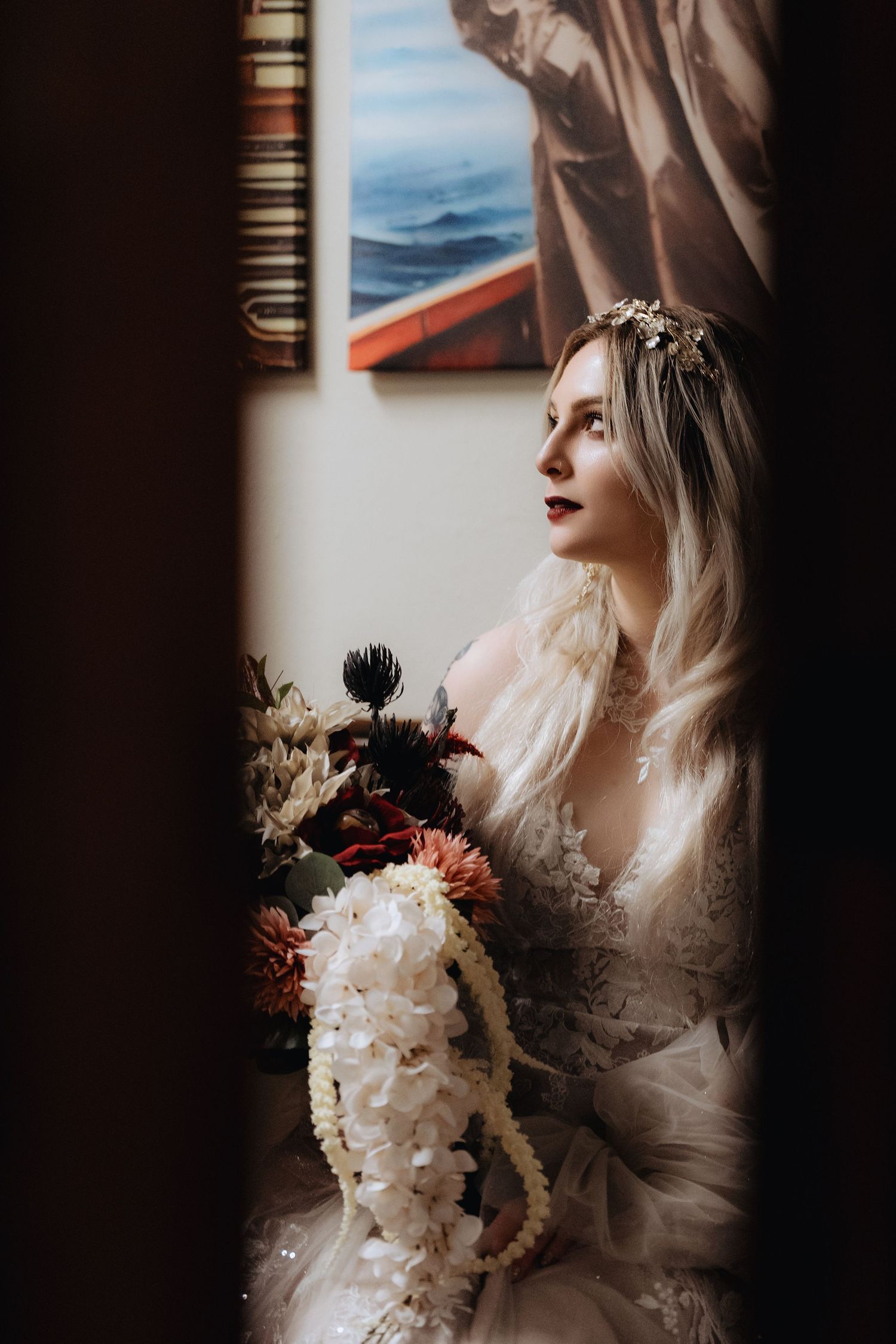 A series of moody bridal portraits showing a white wedding dress and bouquet in dramatic window lighting.