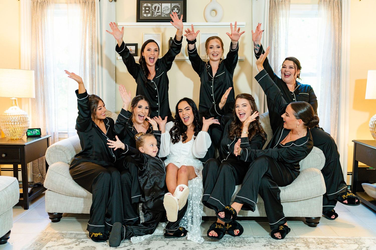 Wedding party in black robes celebrates joyfully on light colored floor.