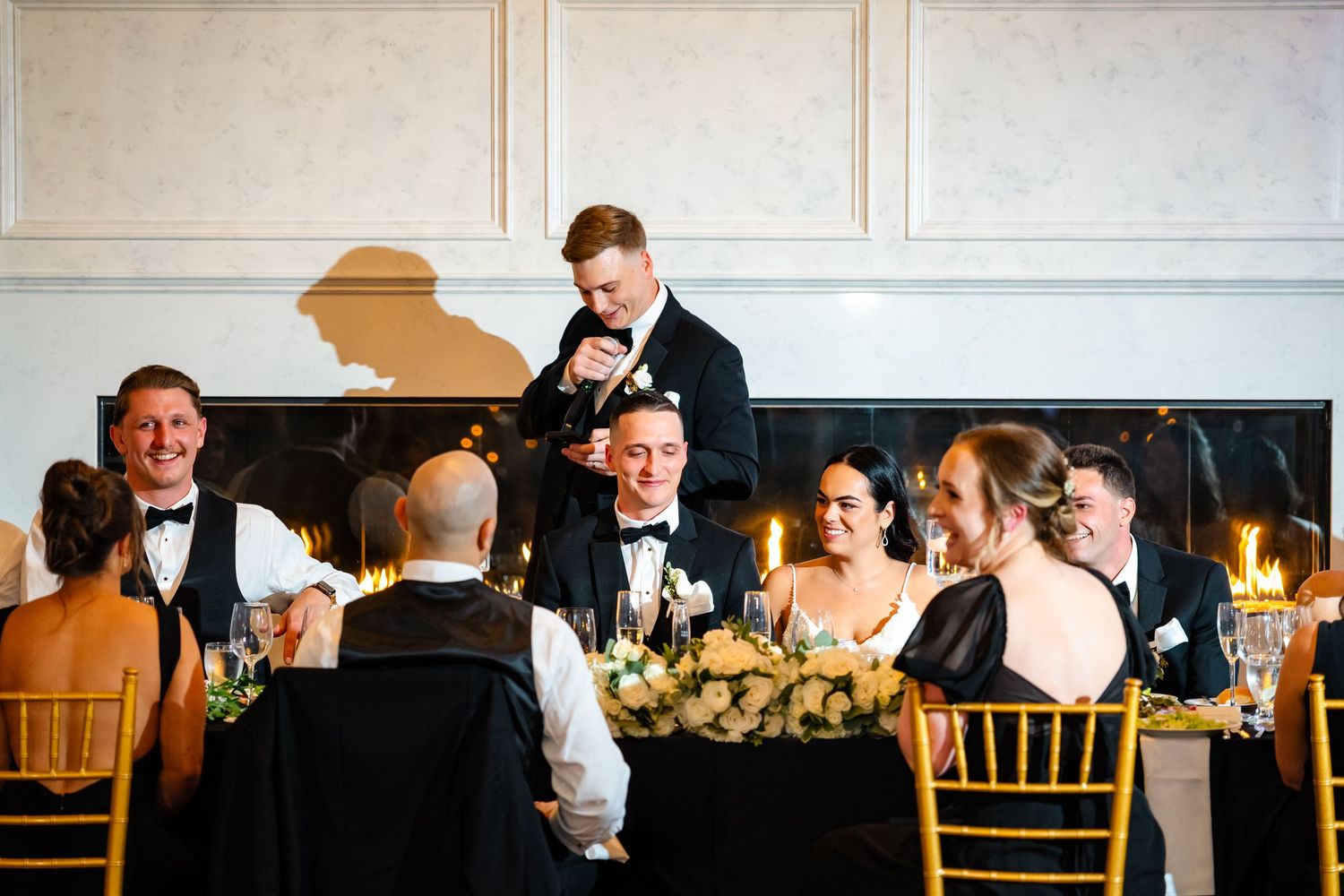 Wedding reception celebration with formal dining tables and decorative lighting in an elegant ballroom.