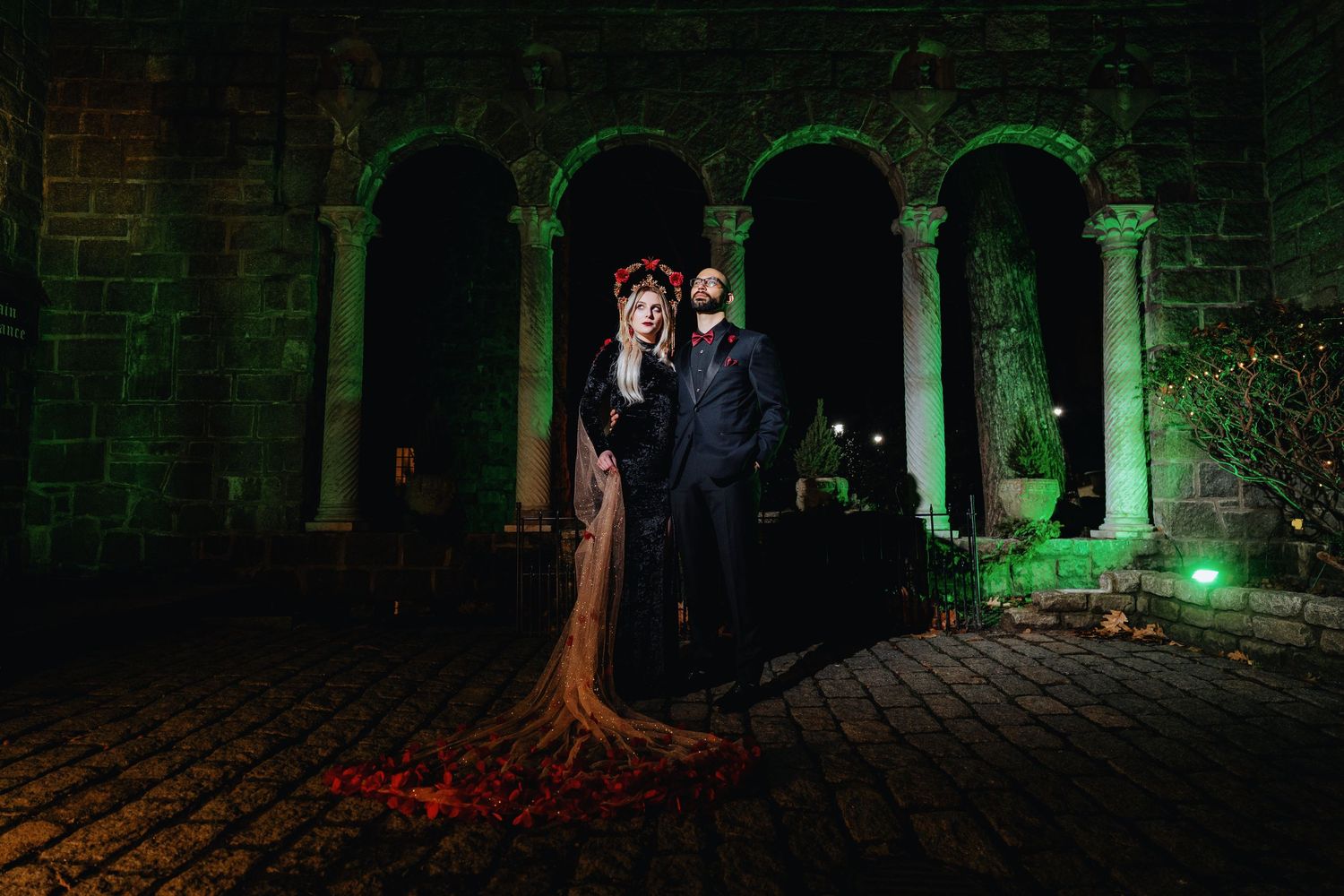 Spooky green-lit stone archways and trees create an eerie atmosphere in a dark outdoor setting at night.