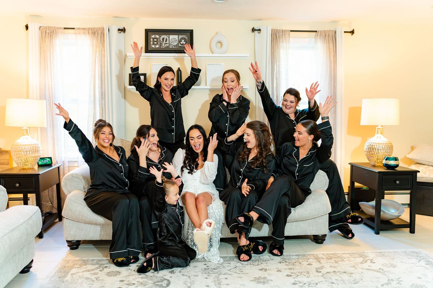 Wedding party relaxes on white furniture during casual pre-ceremony moments.