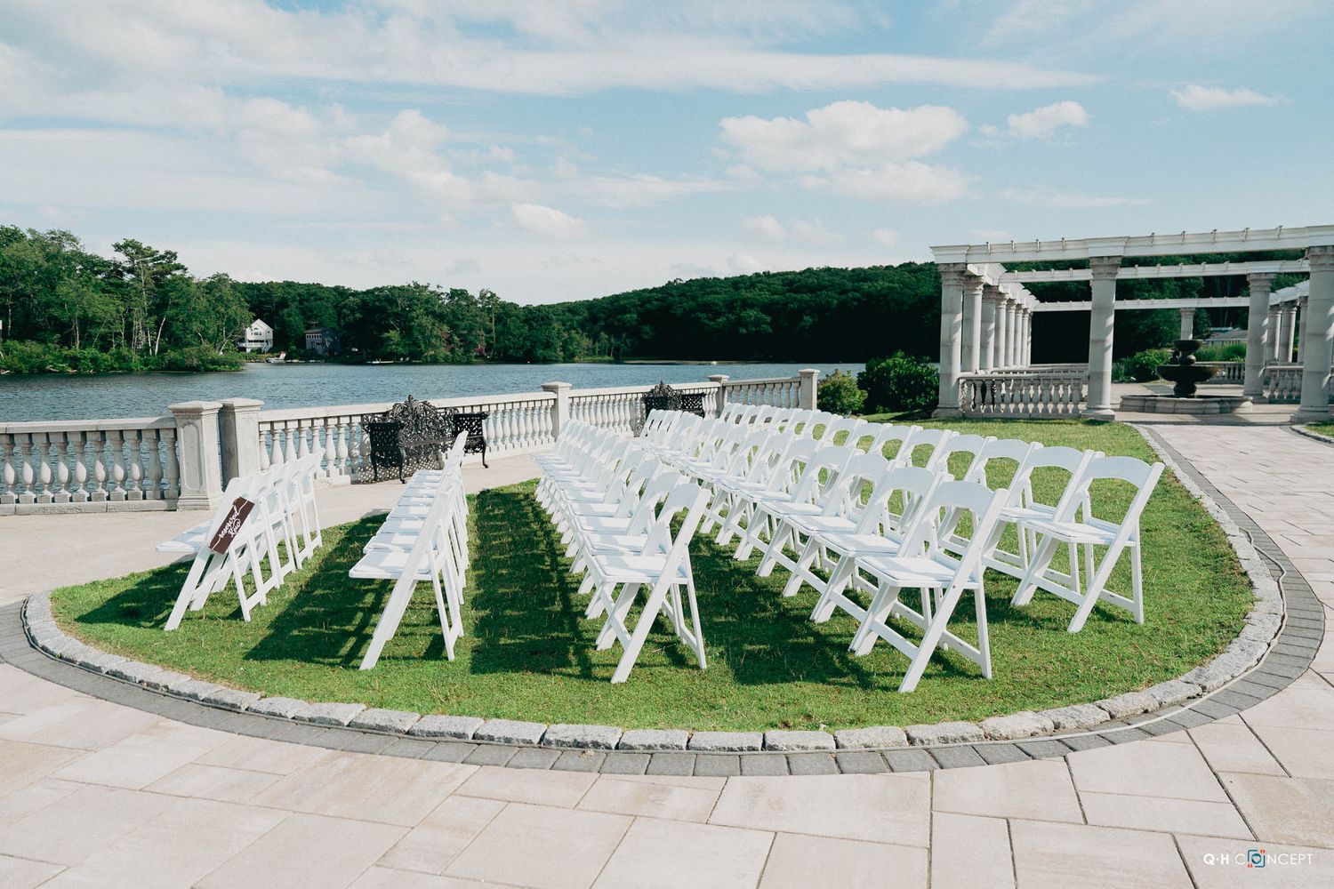 A curved row of white wooden chairs arranged outdoors at a memorial site on a grassy hillside.
