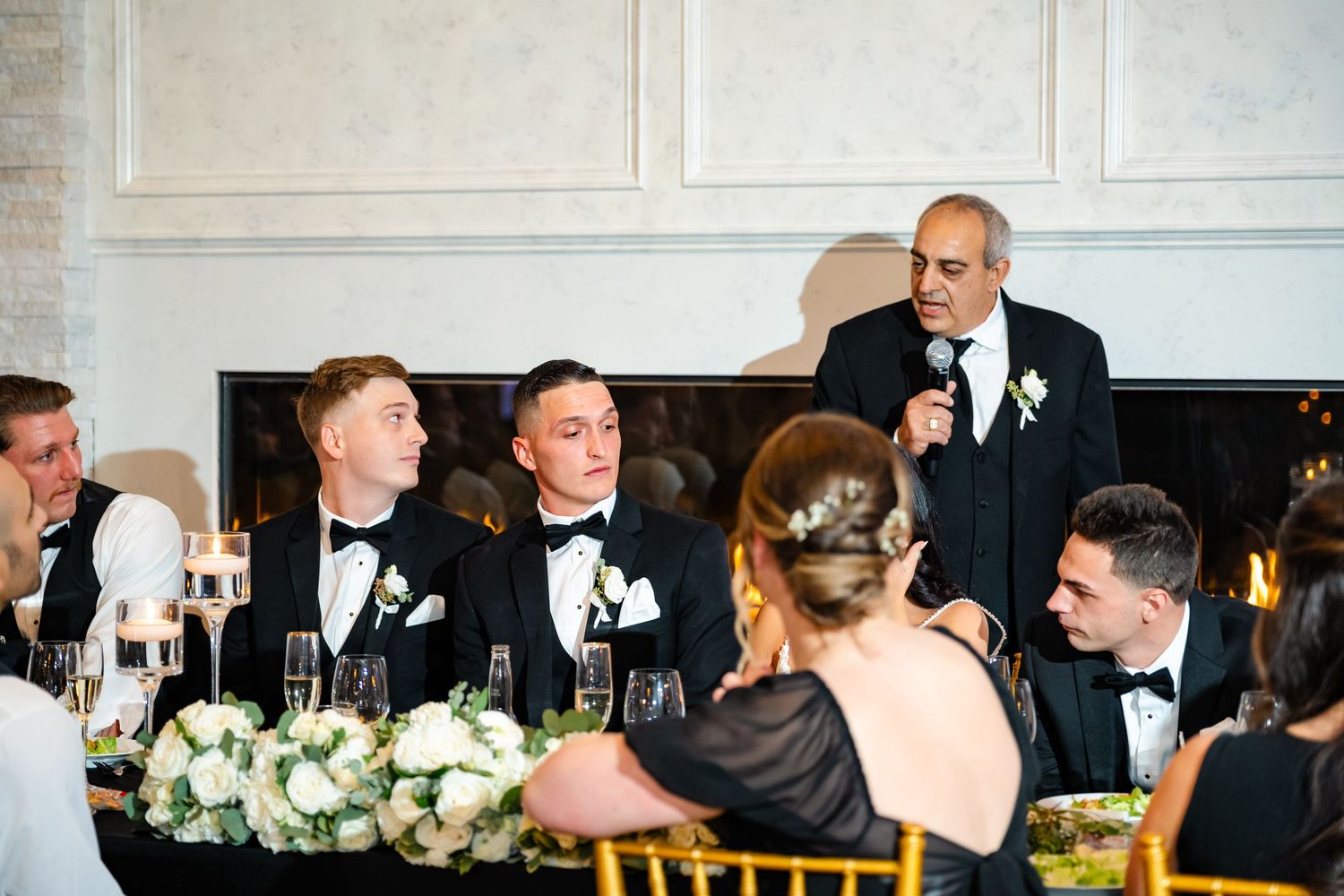 Formal wedding reception setup with elegant table settings and white floral centerpieces.