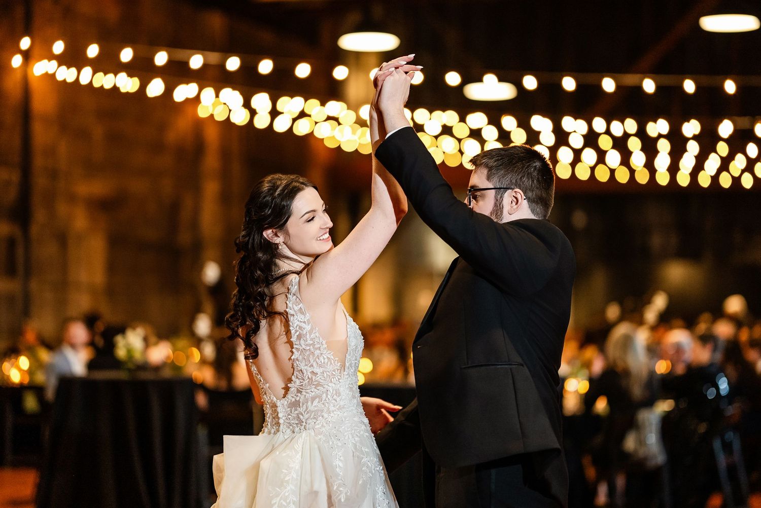 Wedding reception dance under string lights with festive atmosphere.