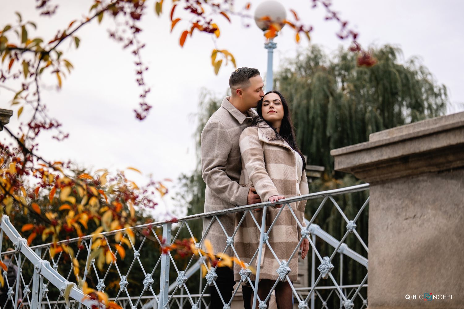 A romantic autumn scene on a decorative bridge with fall colors in the background.
