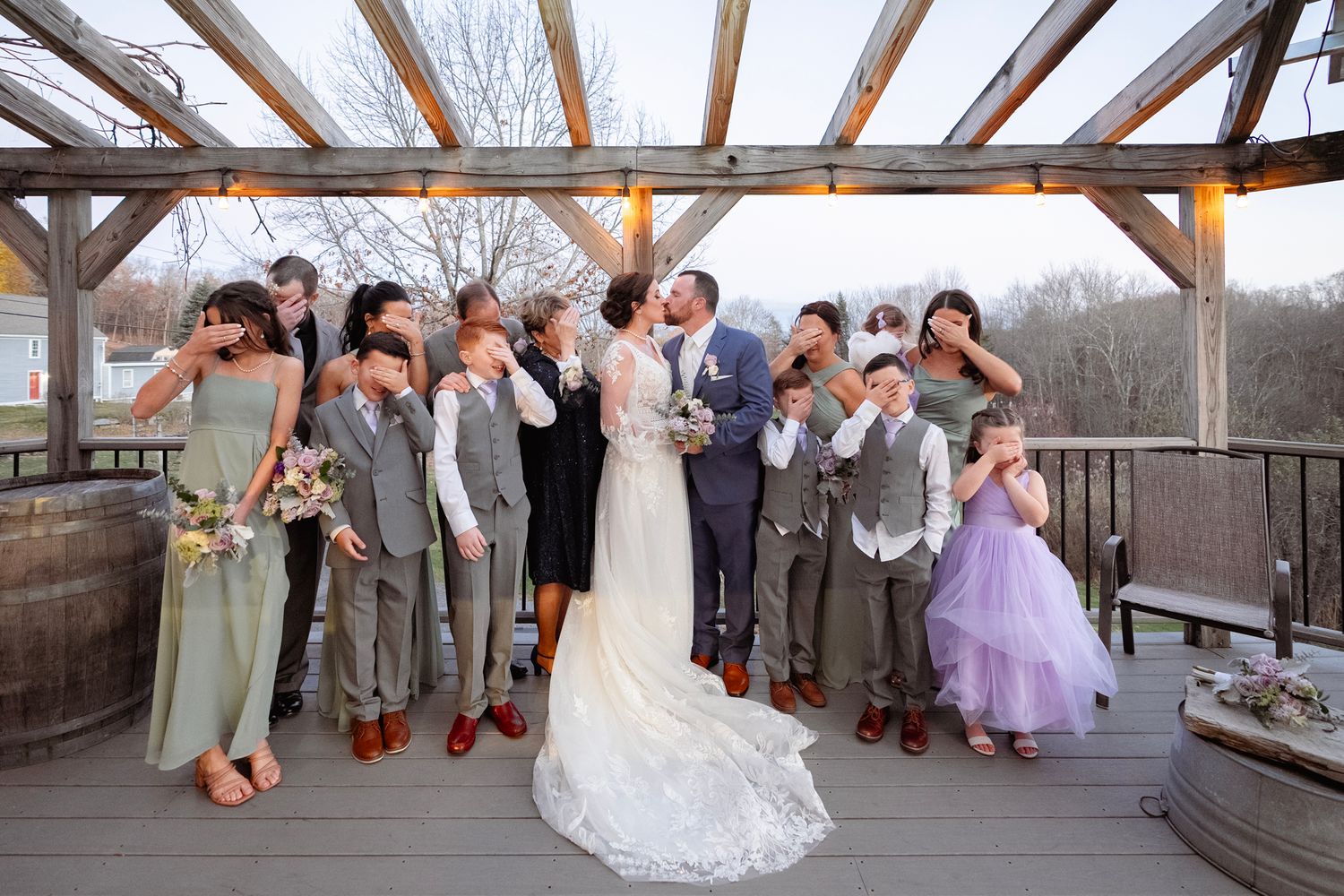 Wedding party poses together on an outdoor deck during a celebration.