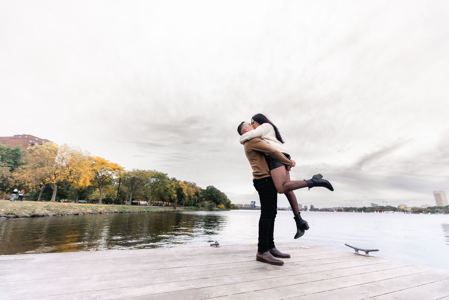 A couple ice skating together on a frozen lake surrounded by autumn trees and nature.