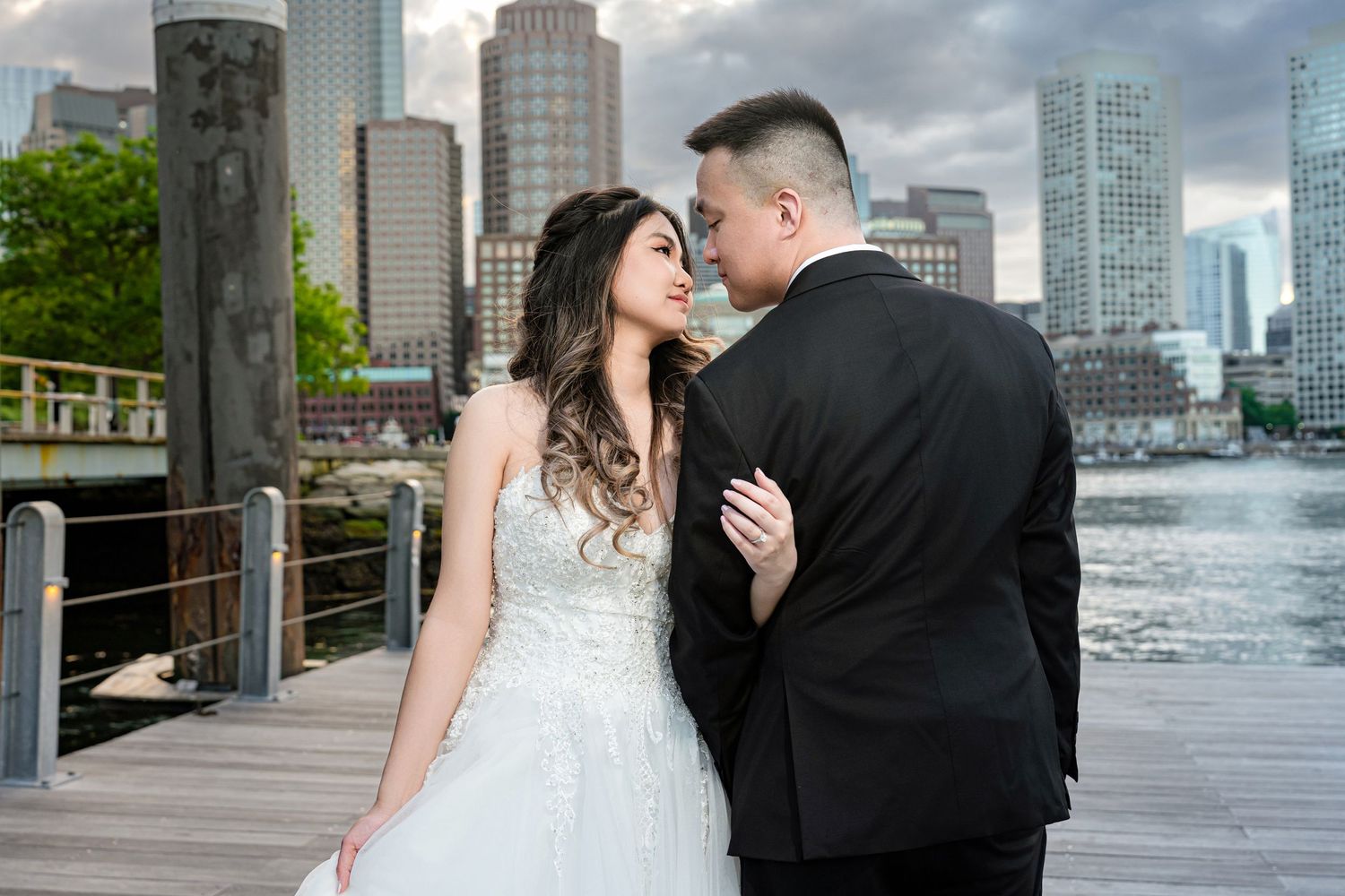 Romantic wedding portraits captured on a waterfront with urban architecture in the background.