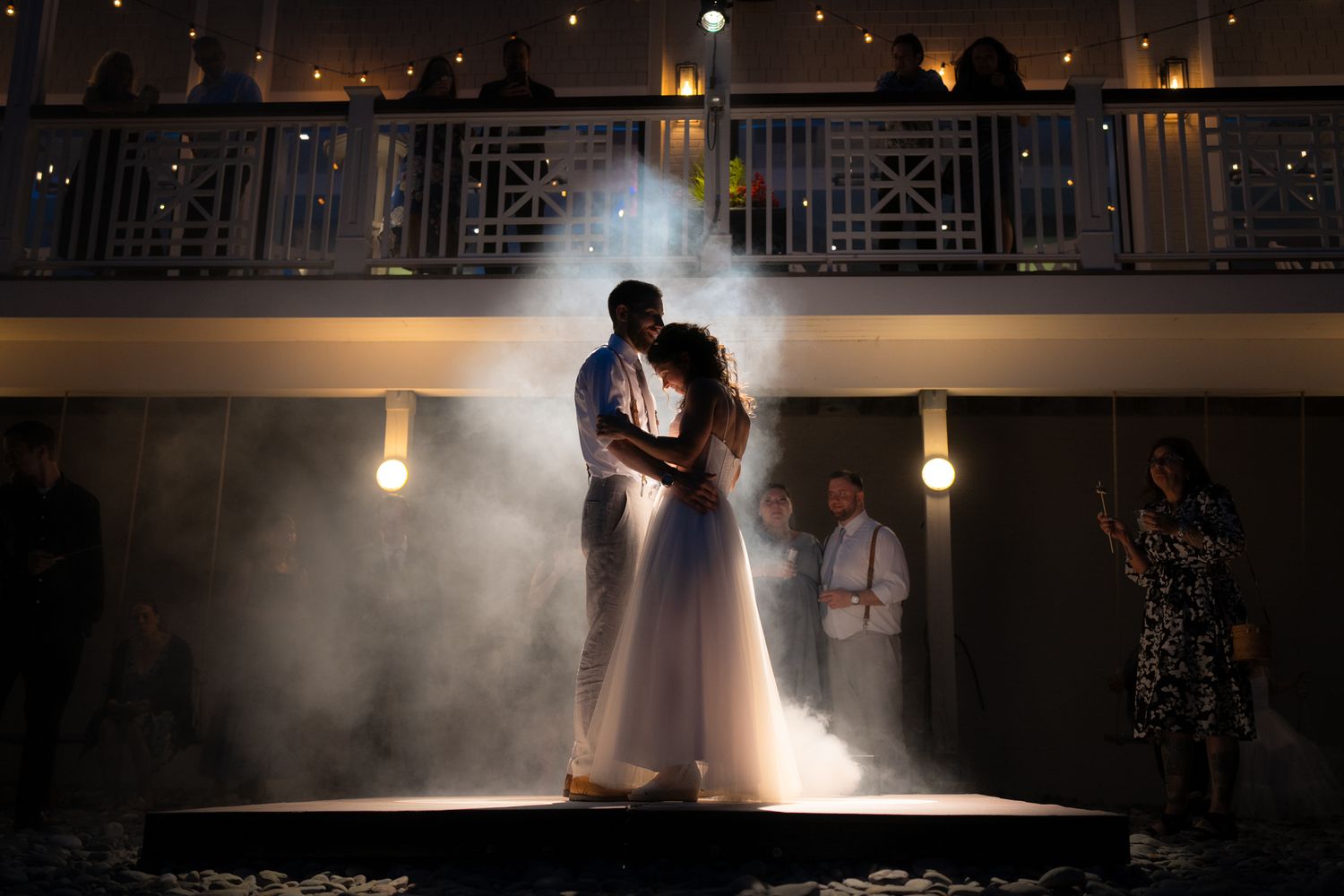 A dramatic backlit silhouette of a couple dancing in fog during their first dance.