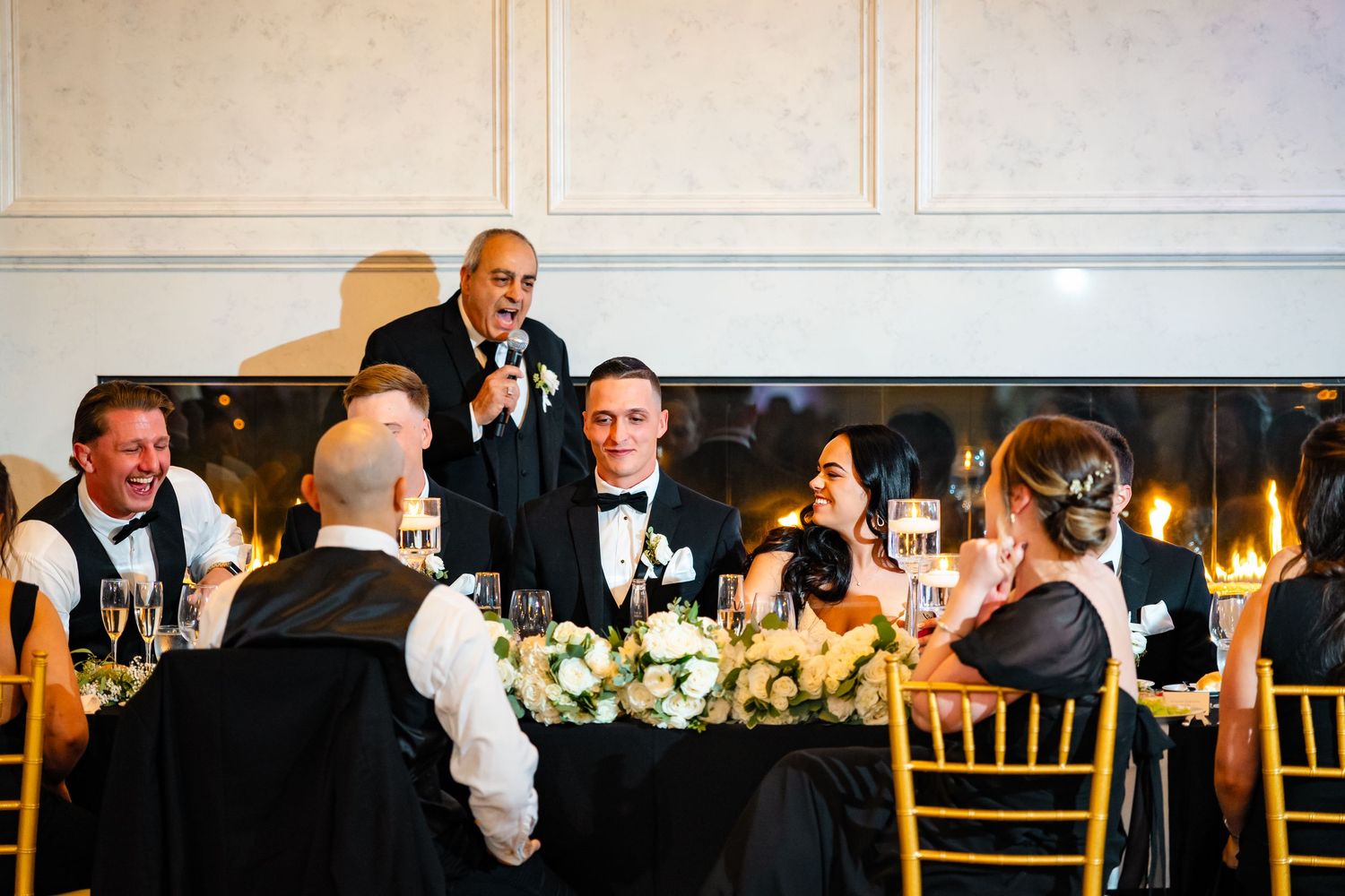 Wedding reception dinner scene with elegant table settings and formal attire.