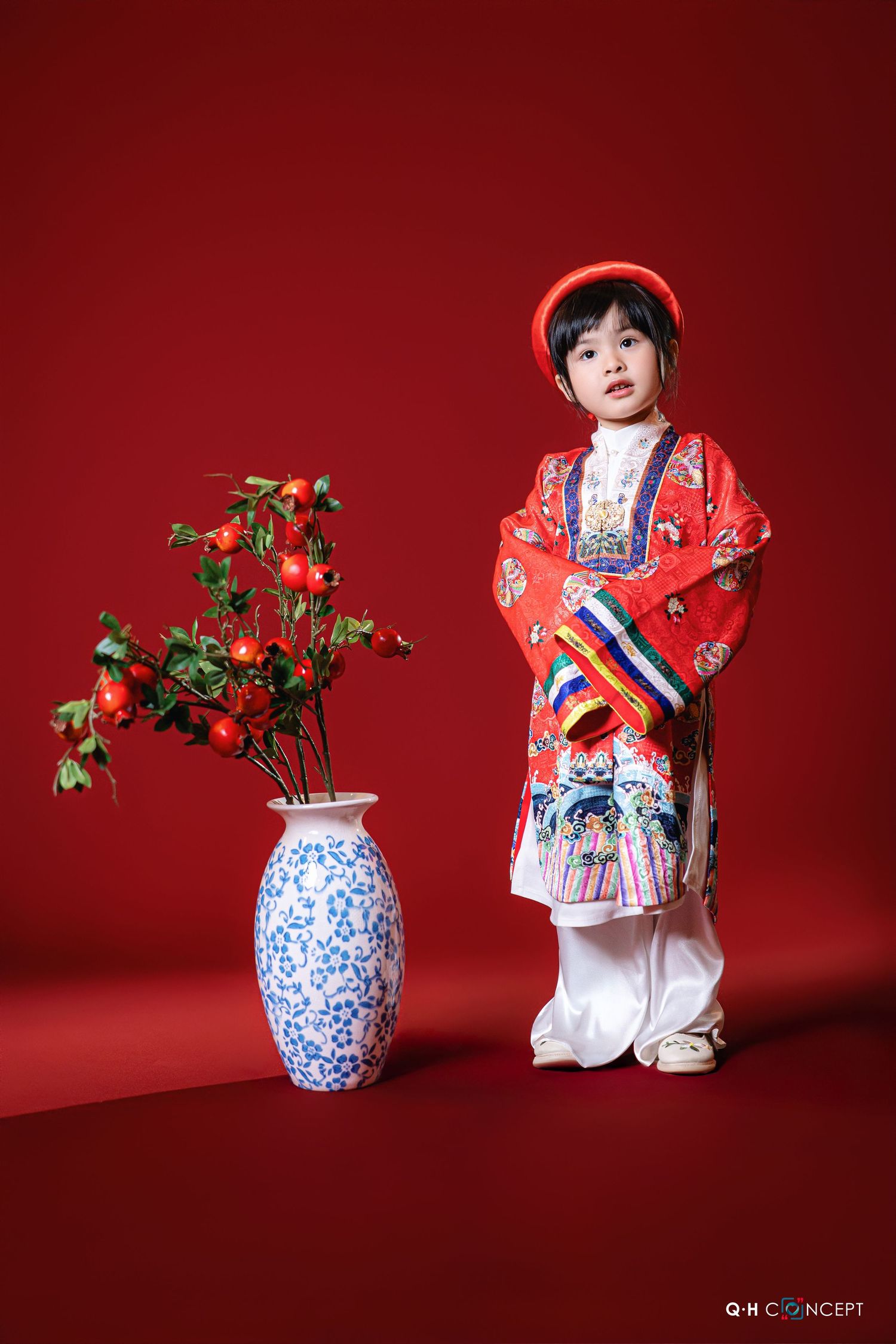 Traditional Asian-inspired photoshoot against red backdrop featuring blue and white porcelain vase with greenery.