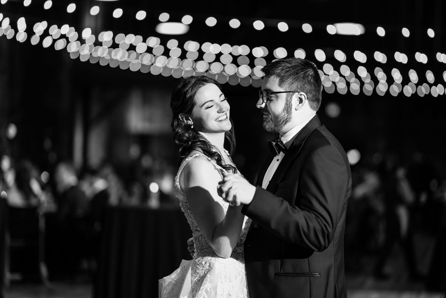Romantic dance moments captured under twinkling lights at evening reception.
