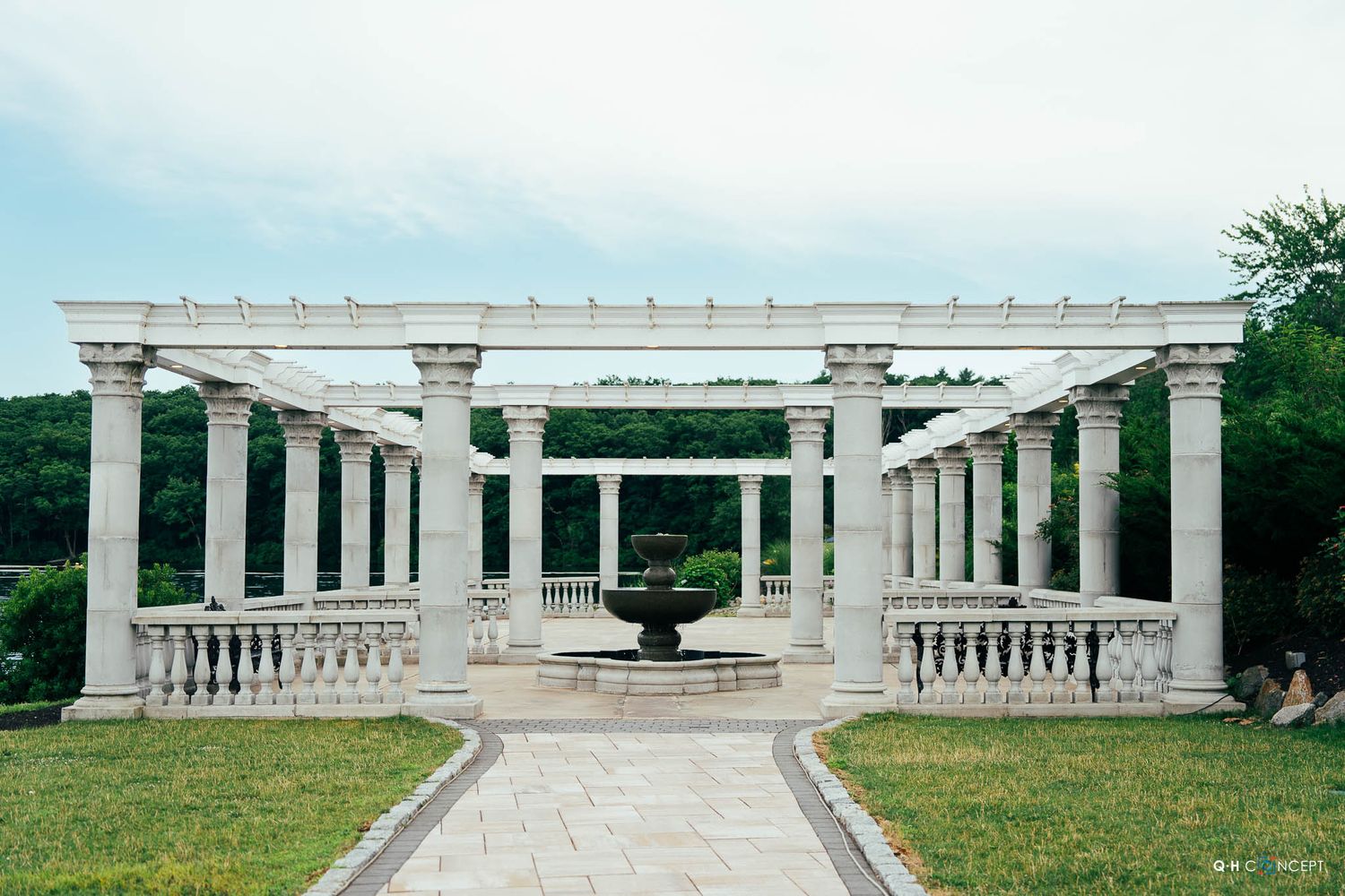 White marble colonnade walkway with pillars and balustrades stretches across a green lawn at the Arlington National Cemetery.