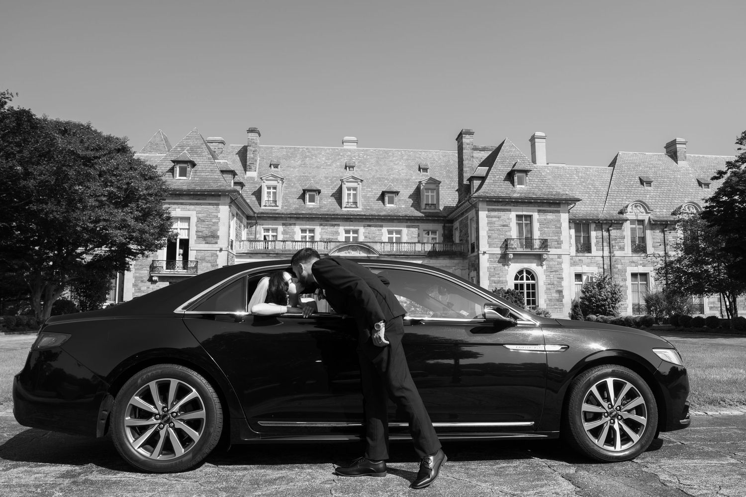 Luxury black Tesla Model S cars parked in a row outside elegant white buildings.