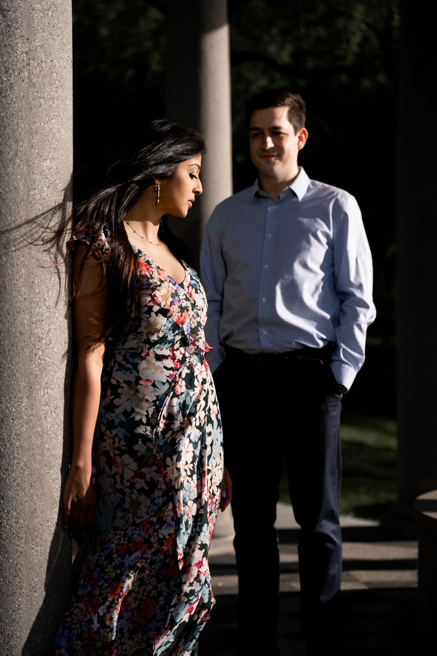 Two people stand between stone pillars with dramatic shadows and lighting.