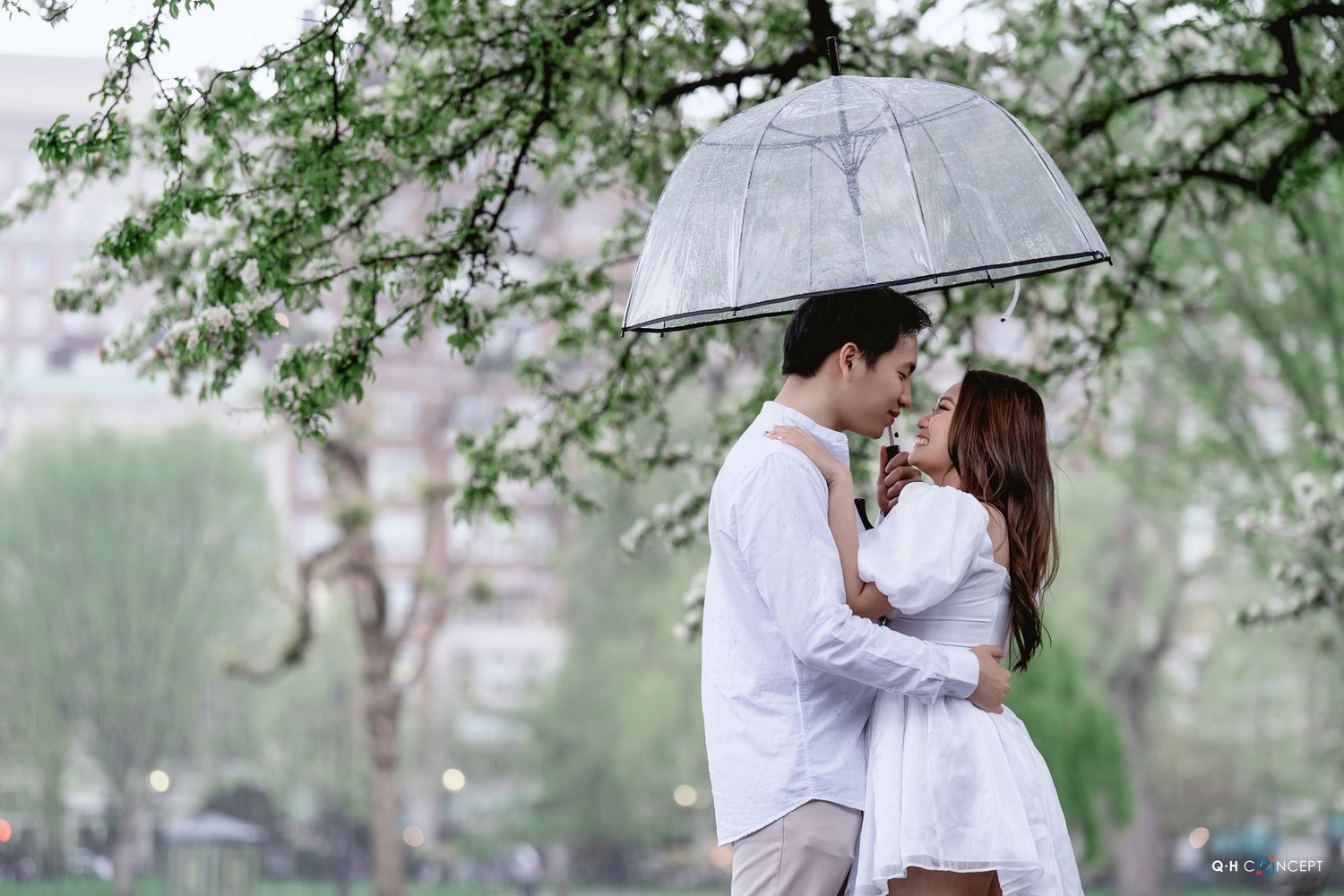 Couple embracing under blooming spring trees in an outdoor garden setting.