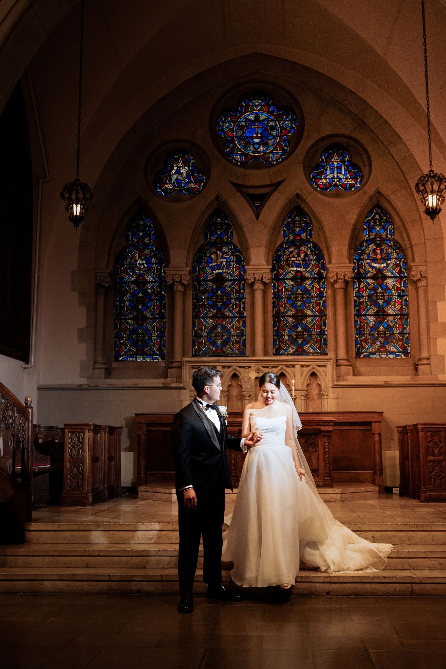 Elegant wedding ceremony in historic church with stunning stained glass windows and gothic architecture.