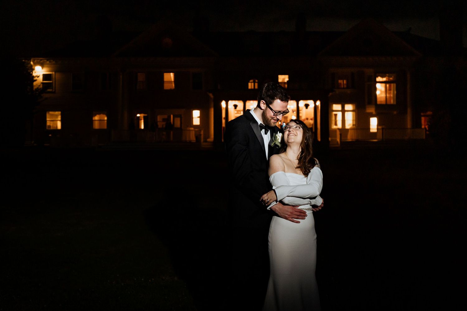 Romantic evening wedding venue with warm glowing lanterns and windows.