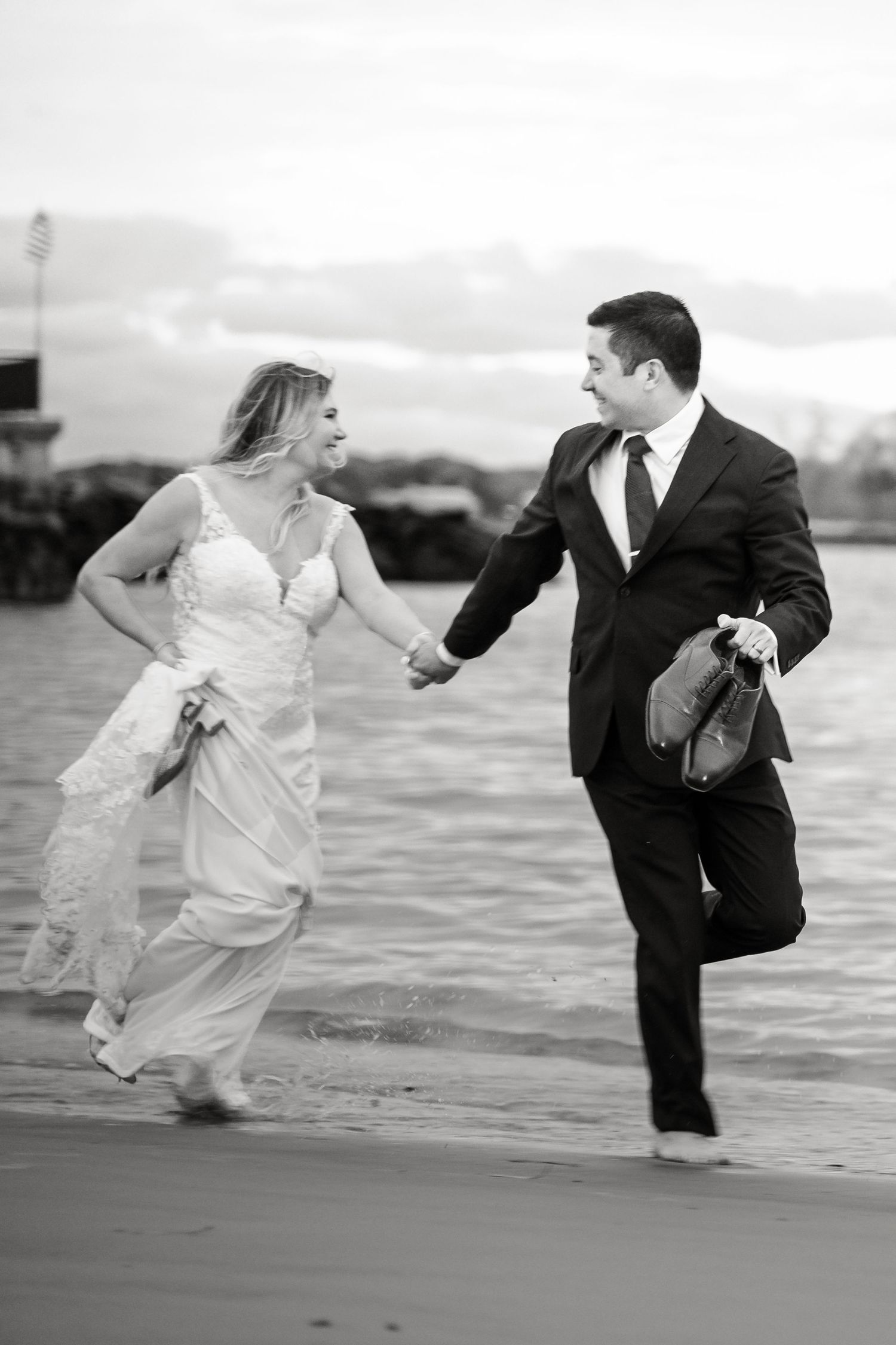 Playful black and white beach portraits with dynamic movement and flowing dress.