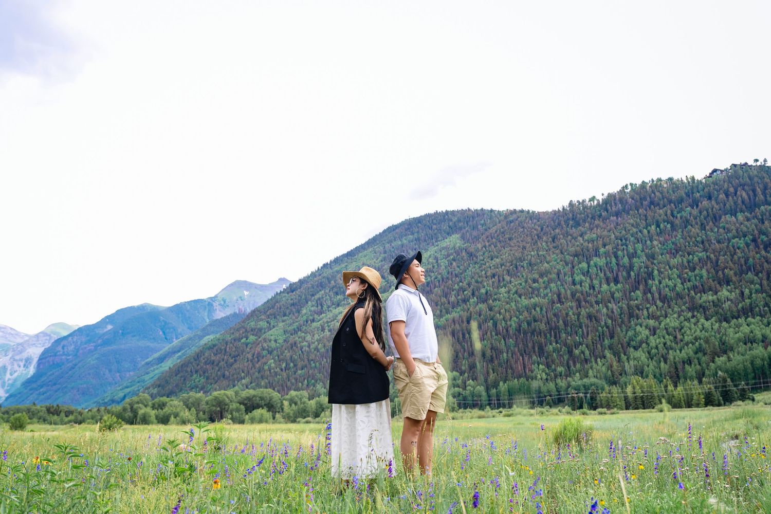 Scenic mountain meadow engagement session with dramatic peaks in the distance.