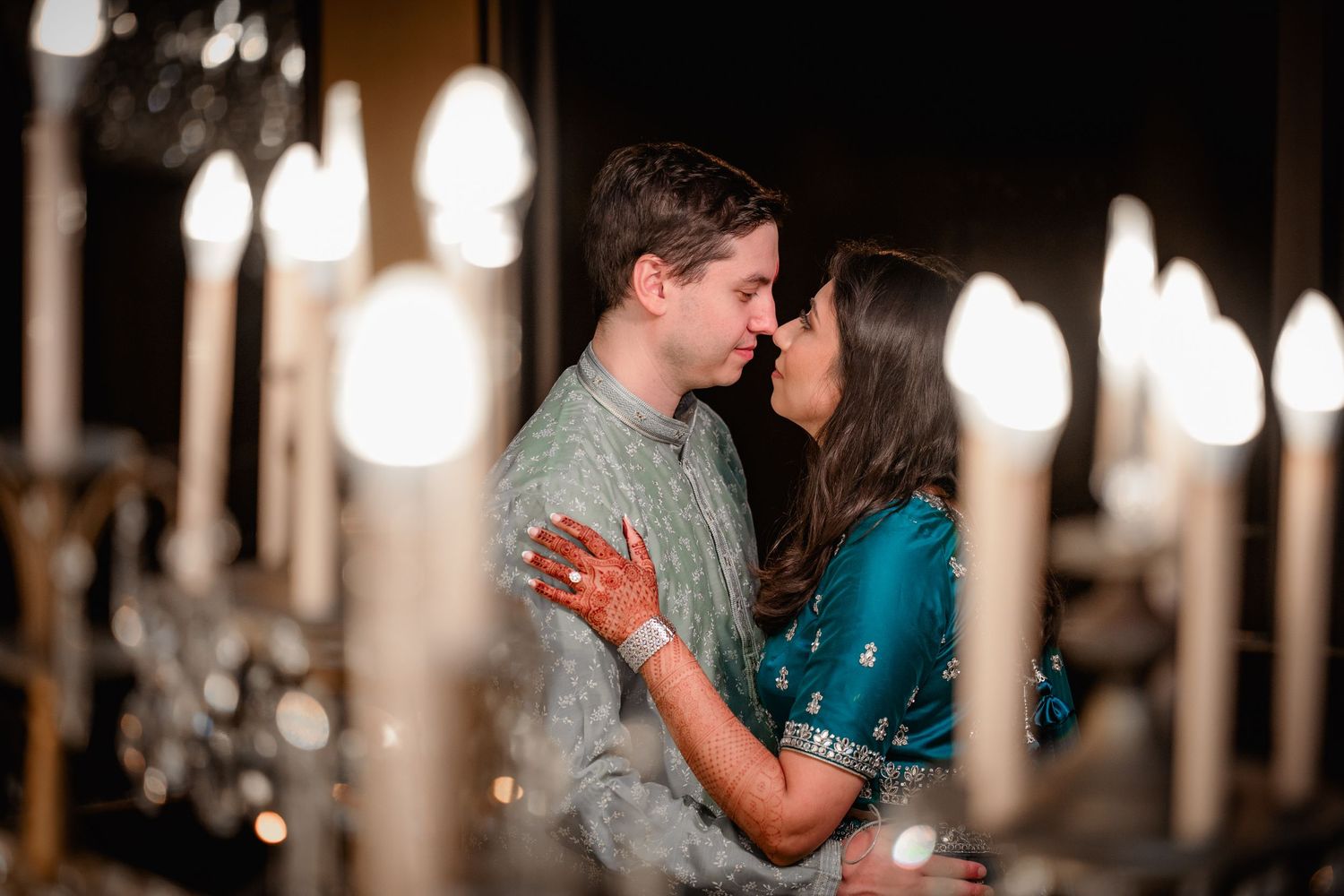 An intimate moment captured in warm lighting with elegant columns and glowing lanterns in the background.