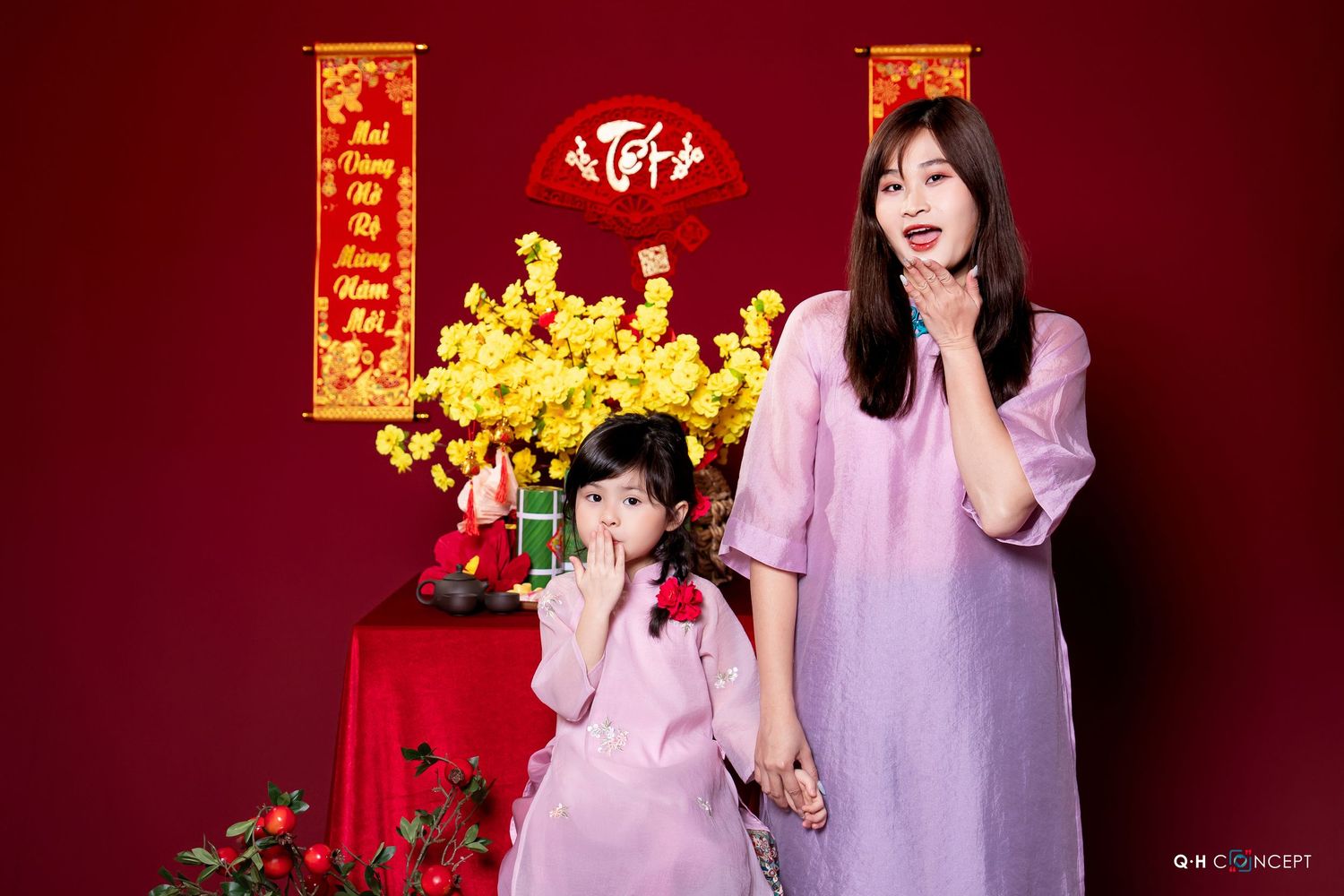 A festive Chinese New Year themed photoshoot with red and gold decorations against a burgundy backdrop.