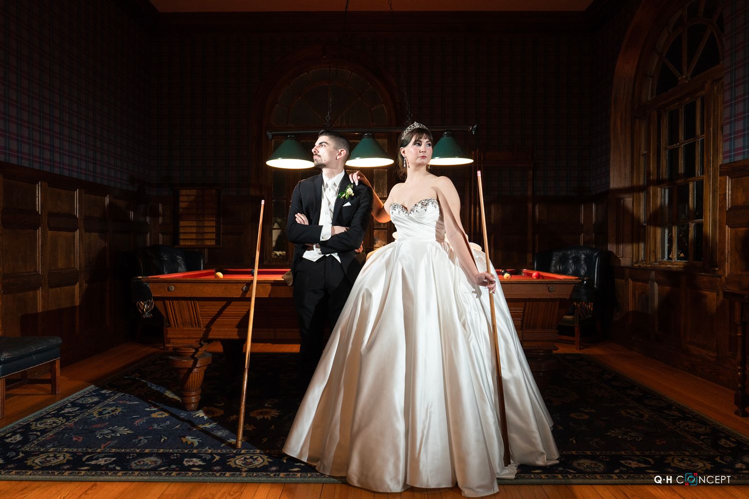 Elegant wedding couple dancing in a dimly lit ballroom with dramatic lighting and shadows.