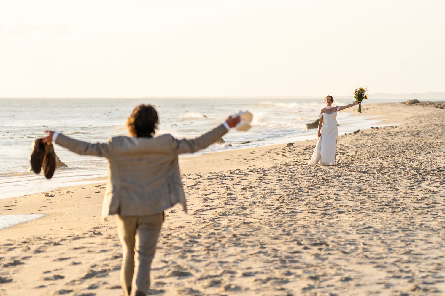 Silhouettes of couple walking along beach at sunset.