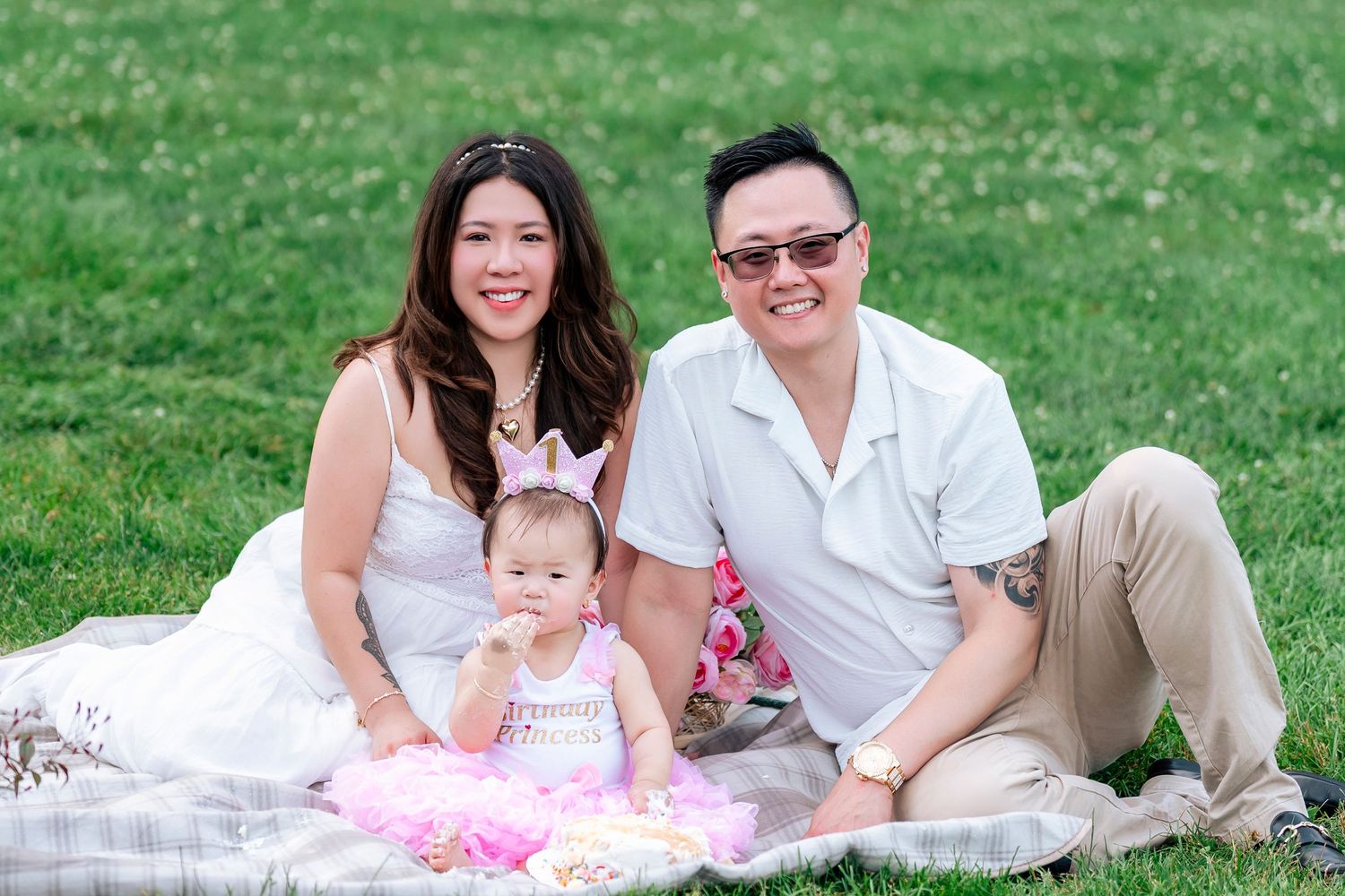 Casual outdoor family photos on grass with white picnic blanket setup.