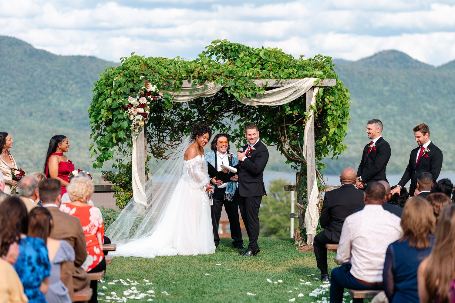 Outdoor wedding ceremony setup with mountain views and white floral arch.