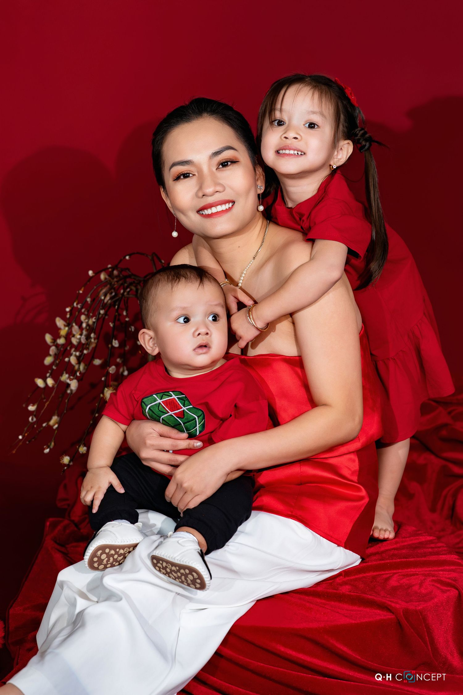 A series of holiday portraits showing a baby and parent in red and white outfits against a dark red backdrop.