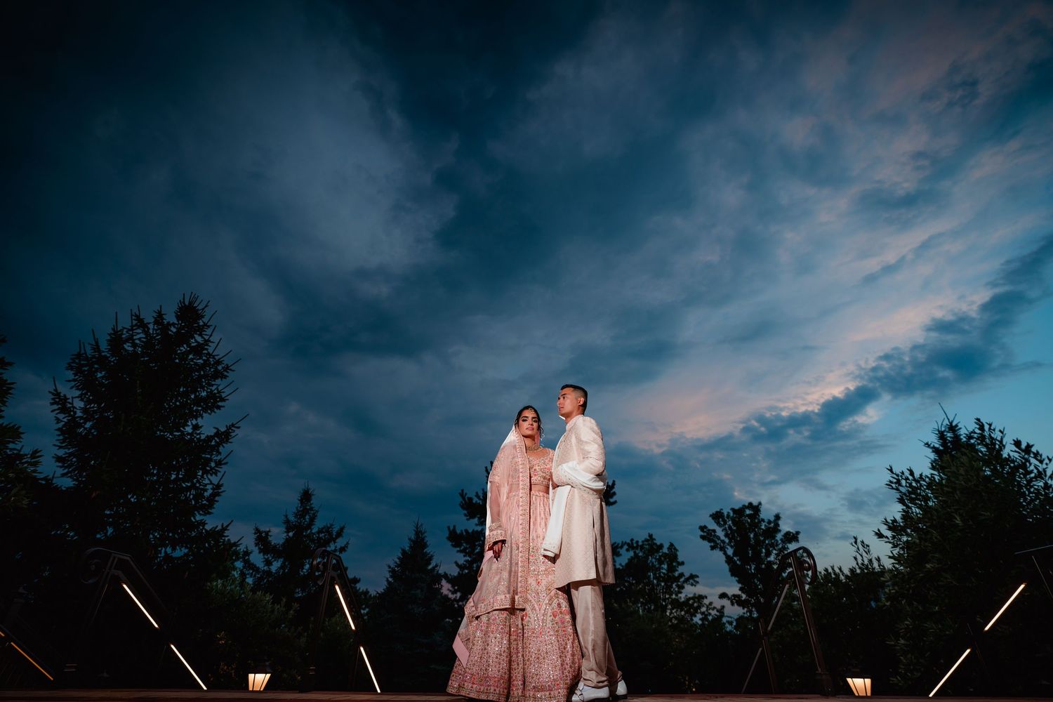 Dramatic moody blue sky with clouds creates atmospheric backdrop for wedding photography.