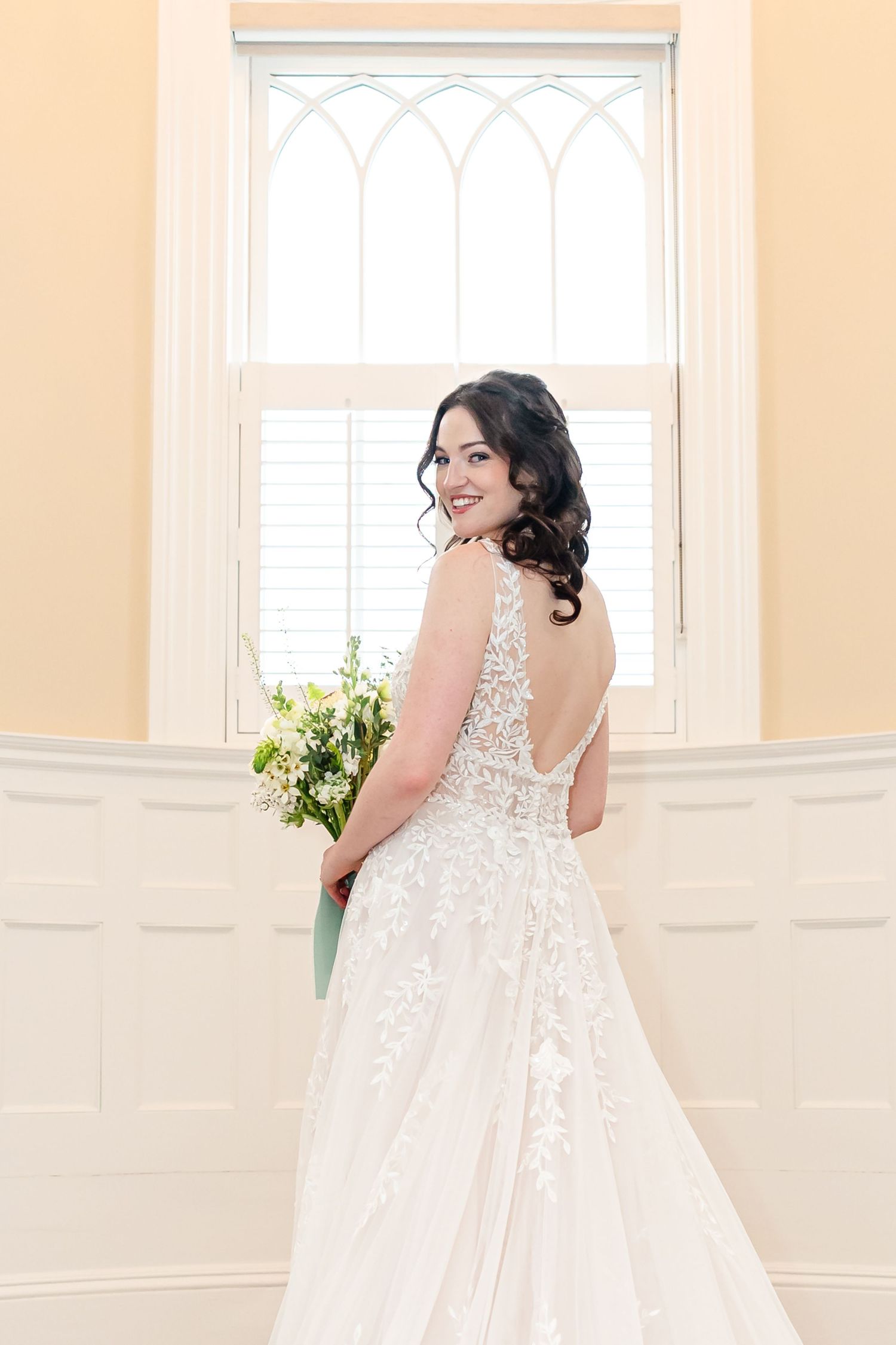 Light-filled bridal portraits showing the intricate back details of a lace wedding gown.
