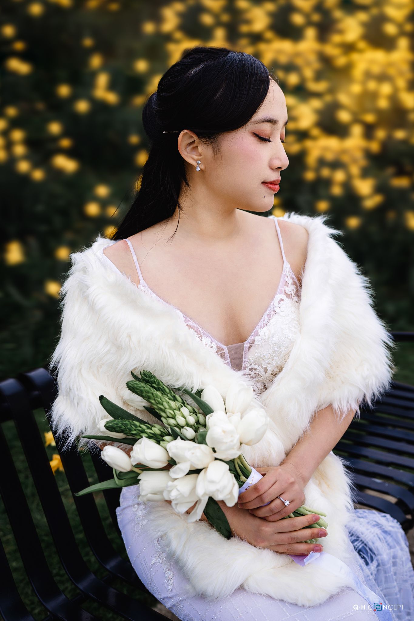 Bridal portrait with white fur wrap and tulip bouquet against golden bokeh background.