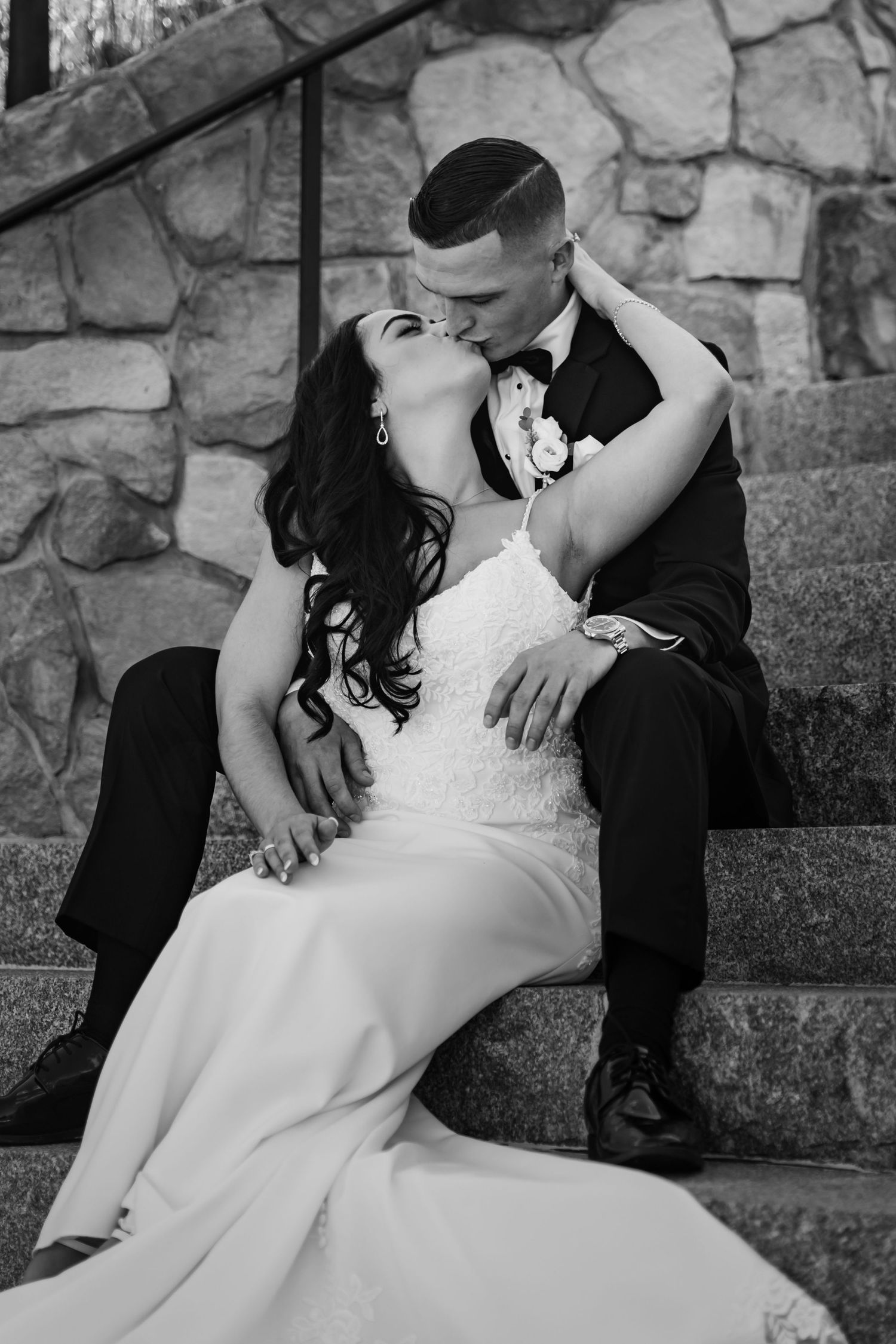 Black and white portrait of newlyweds sitting on stone steps together.