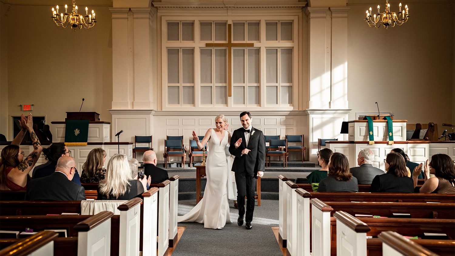 Wedding ceremony setup in an elegant church with chandeliers and wooden pews.