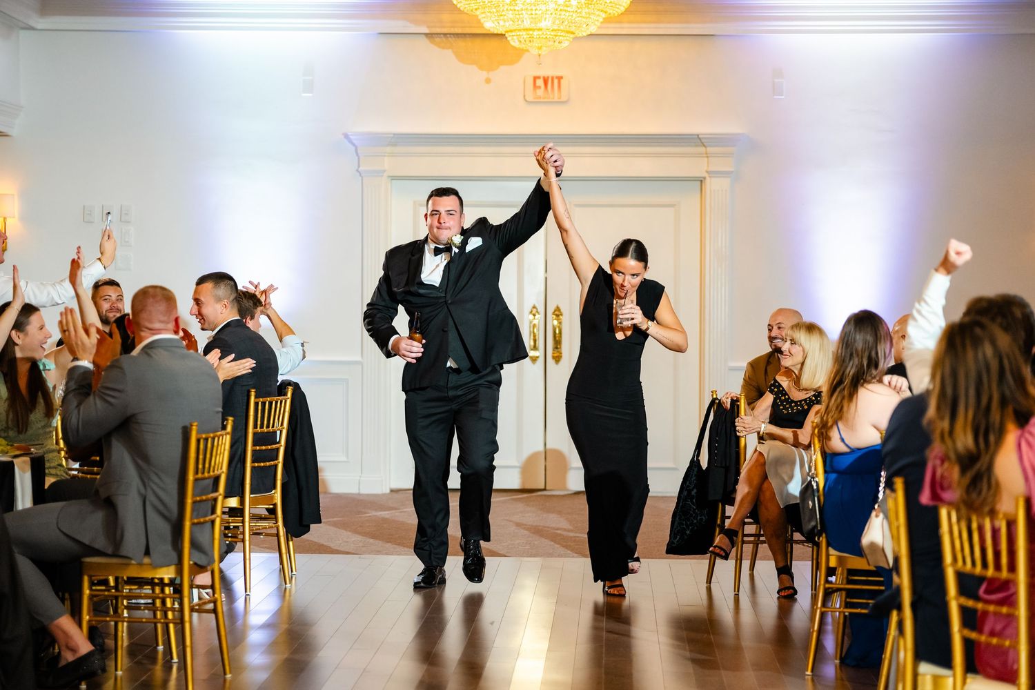Celebratory entrance of wedding party into reception venue with cheering guests.