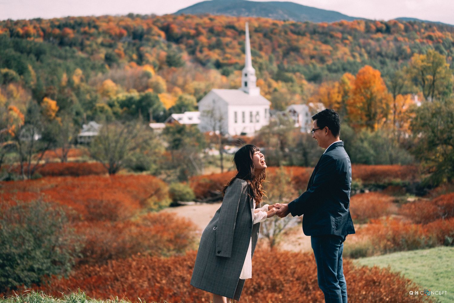 Fall landscape with rolling hills covered in autumn colors and white church in distance.