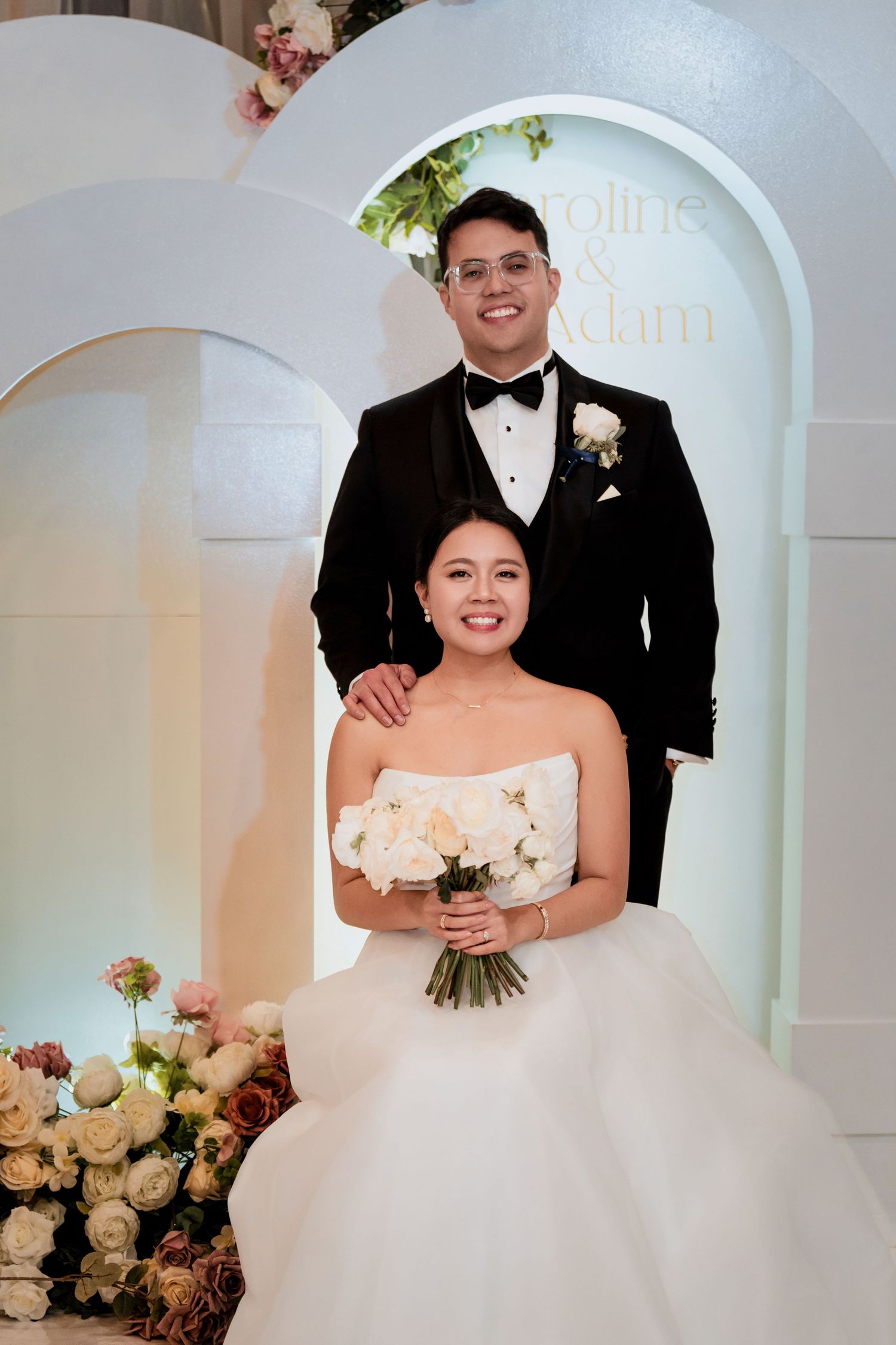 Wedding celebration in an elegant white room with arched doorways and floral decorations.