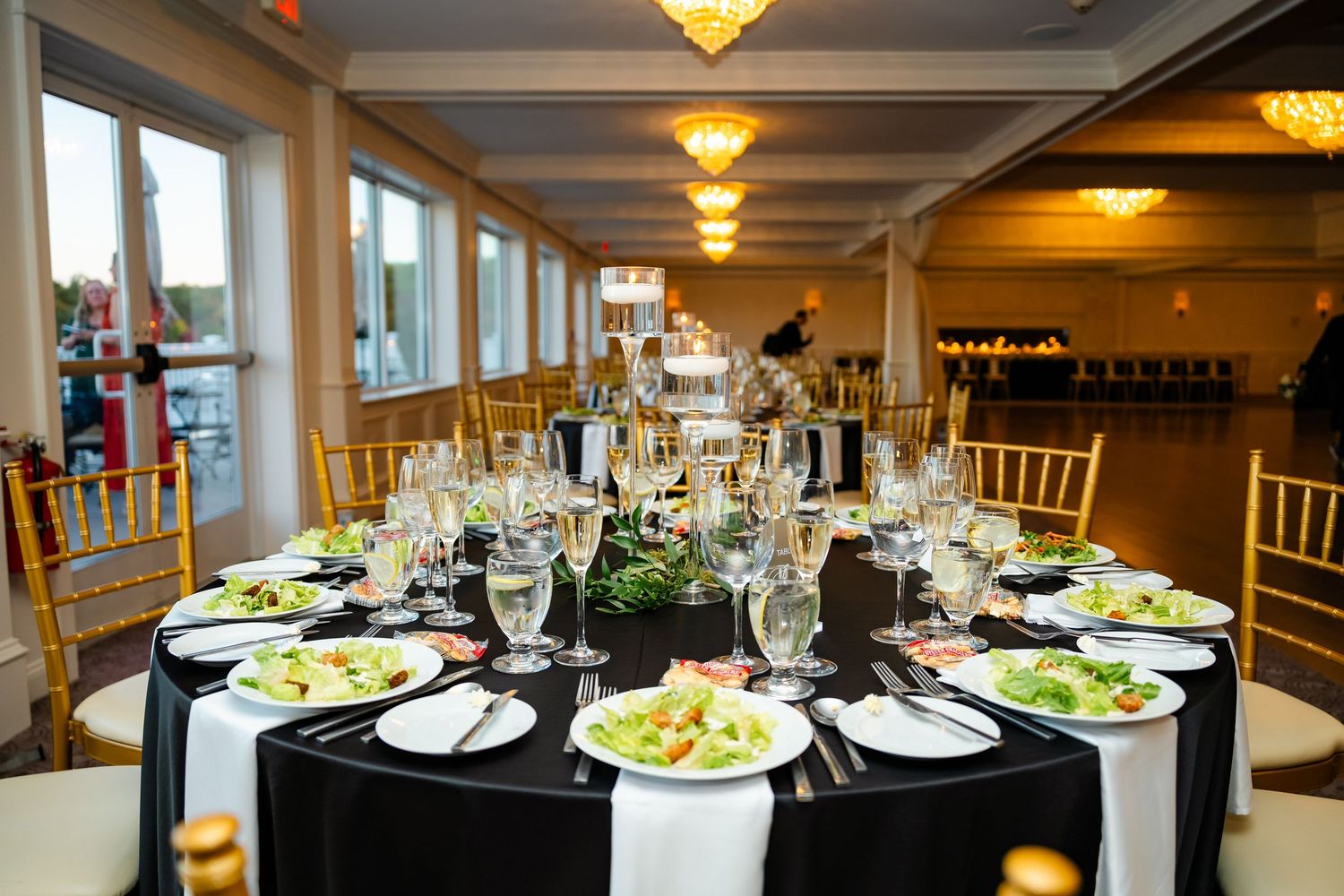 Reception tables set with formal place settings and centerpieces in an elegant banquet hall.